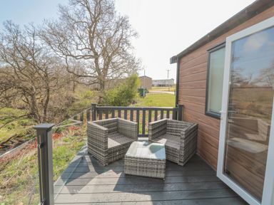 An outdoor balcony with two wicker chairs and a wicker table at Dreams & Streams in Bockenfield Country Park near West Thirston