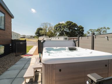 An outdoor hot tub with bubbling water next to a small table with wine and glasses at Dreams & Streams Bockenfield Country Park near West Thirston