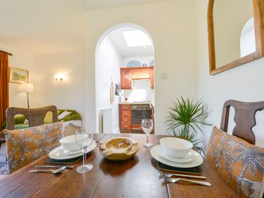 A dining table set with bowls glassware and cutlery with a wooden bowl in a room leading to a kitchen at Little Barton in Stogumber near Watchet