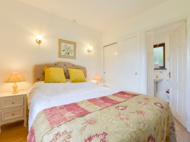 A bedroom with a bed featuring yellow pillows and a patterned cover at Little Barton in Stogumber near Watchet