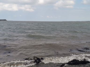 A view of the sea with waves and seaweed near the shore under a cloudy sky at Beach Reach in Valley