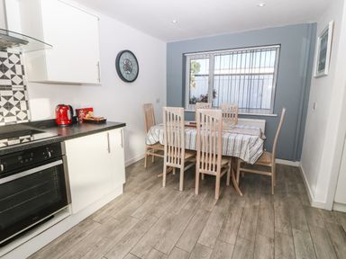A dining area with a table and six chairs next to a kitchen with white cabinets and a red kettle at Beach Reach in Valley