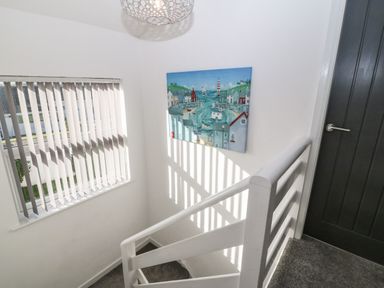 A stairway with white railing next to a window with vertical blinds and a wall painting at Beach Reach in Valley