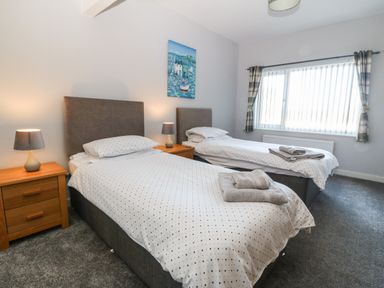 A bedroom with two single beds bedside tables lamps a window and a painting at Beach Reach in Valley