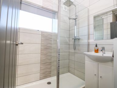 A bathroom with a shower enclosure sink with soap dispenser and mirror at Beach Reach in Valley
