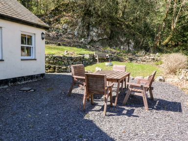An outdoor patio area with wooden table and chairs near a white building at Greffyn in Betws Y Coed