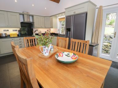 A kitchen with a dining table and refrigerator at Greffyn in Betws-Y-Coed