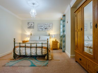 A bedroom with a metal bed frame and wooden wardrobe at Jasmine Cottage in Mickleton Gloucestershire