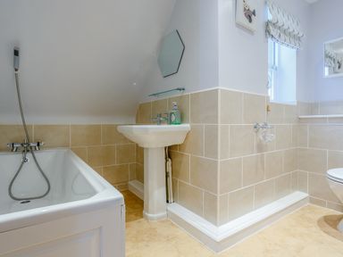 A bathroom with a bathtub a sink a toilet and a window at Jasmine Cottage in Mickleton Gloucestershire