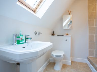 A bathroom with a white sink and toilet under a skylight at Jasmine Cottage in Mickleton Gloucestershire
