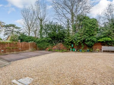 An outdoor area with gravel ground parking spaces wooden fence potted plants and a bench in the garden at Jasmine Cottage in Mickleton Gloucestershire
