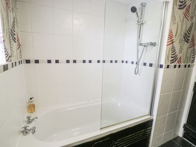 A bathtub with a shower at Orsedd Wen Farmhouse in Betws-Y-Coed