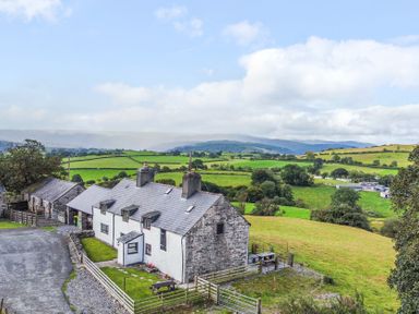 A farmhouse with surrounding fields and mountains at Orsedd Wen Farmhouse Betws-Y-Coed