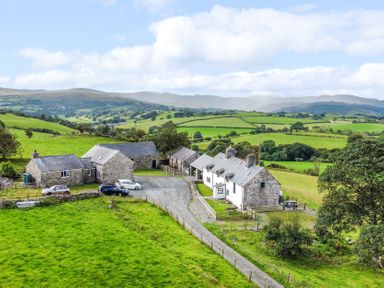 A farmhouse with several buildings and cars at Orsedd Wen Farmhouse in Betws-Y-Coed
