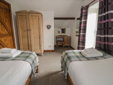 A bedroom with beds and a wardrobe at Orsedd Wen Cottage Betws-Y-Coed
