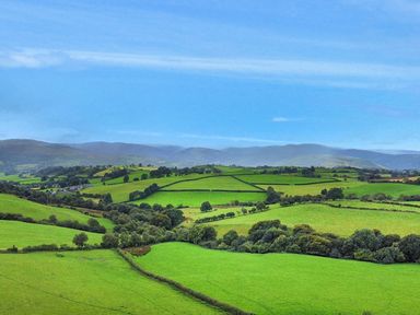 A panoramic view of green fields and hills at Orsedd Wen Cottage in Betws-Y-Coed