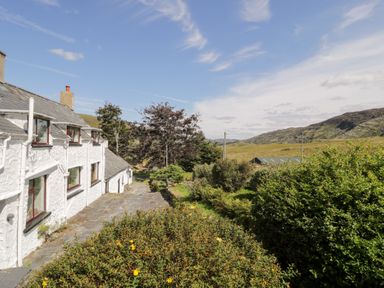 A house with a garden and hills in the background at Cwm, Capel Curig