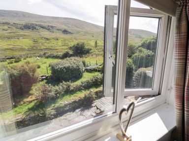 A window view of a garden and hills at Cwm in Capel Curig