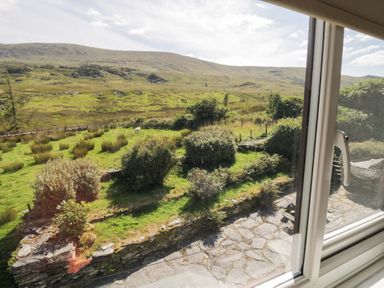 A view of mountains and garden from a window at Cwm in Capel Curig
