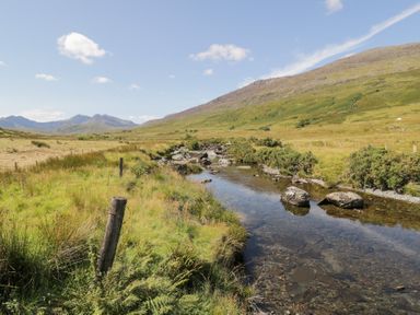 A scenic view of mountains and a stream in Cwm, Capel Curig