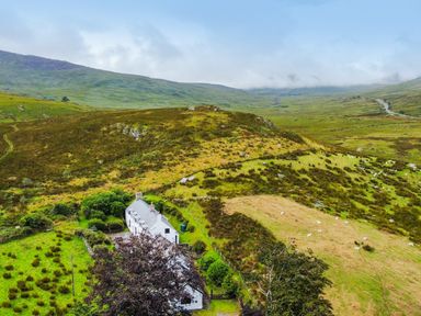 An aerial view of a house surrounded by hills and grassland at Cwm in Capel Curig