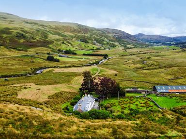A cottage surrounded by trees and fields in Cwm, Capel Curig
