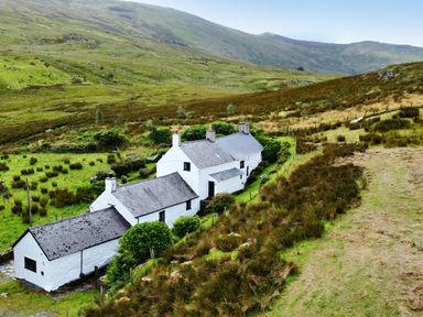 A cottage surrounded by grass and hills at Cwm in Capel Curig