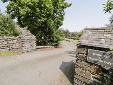 An outdoor area with stone wall and sign at Pengwern Bach in Llanrwst