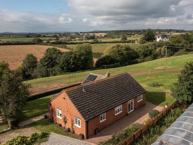 A red brick single-story house with a tiled roof and solar panels in a rural setting at Overbrook in Salwarpe near Droitwich Spa