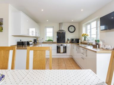 A kitchen with white cabinets wooden countertops and a polka dot tablecloth at Overbrook in Salwarpe near Droitwich Spa