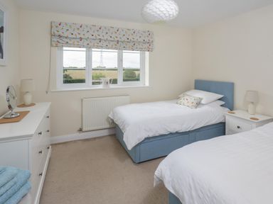 A bedroom with two single beds a window with a patterned blind and a white dresser at Overbrook in Salwarpe near Droitwich Spa