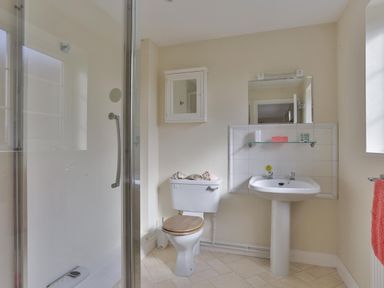 A bathroom with a shower enclosure a toilet with a wooden seat a pedestal sink and a mirror cabinet above at Overbrook in Salwarpe near Droitwich Spa
