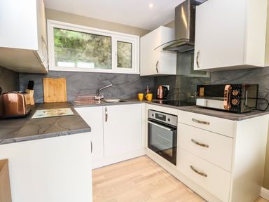 A kitchen with white cabinets a stainless steel oven a microwave toaster kettle and a window at Chalet 126a in Cromer