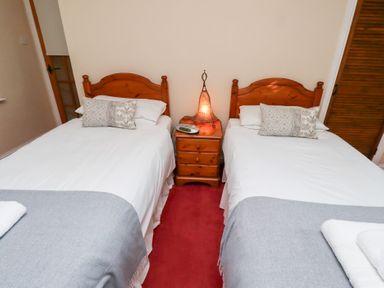 A bedroom with two single beds bedside table with lamp and radio at Rose Cottage in Akeld near Wooler