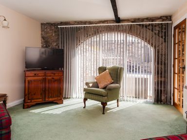 A living room with a television and an armchair at Lupin Cottage near Wooler