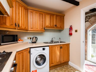 A kitchen with appliances and wooden cabinets at Lupin Cottage in Akeld near Wooler