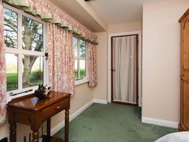 A bedroom with windows and green carpet at Lupin Cottage in Akeld near Wooler