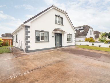 A white house with gray trim a concrete driveway and a small lawn at 17 Clover Hill in Killorglin County Kerry