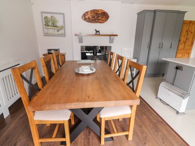 A dining room with a wooden table and six wooden chairs next to gray cabinets and a wall heater at 17 Clover Hill in Killorglin County Kerry