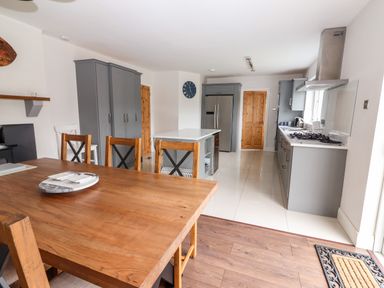 A kitchen and dining area with a wooden dining table and chairs grey cabinets and a kitchen island at 17 Clover Hill in Killorglin County Kerry