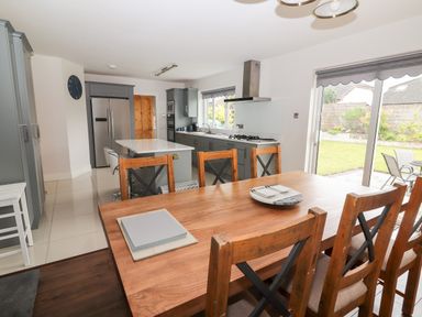 A kitchen and dining area with wooden chairs a wooden table and grey cabinets at 17 Clover Hill in Killorglin County Kerry