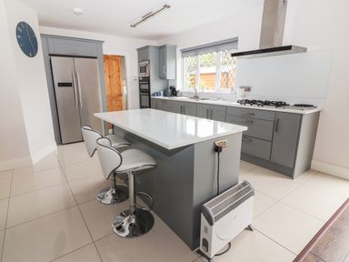 A kitchen with a central island and two bar stools at 17 Clover Hill in Killorglin County Kerry