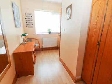 A small room with a wooden desk chair and wardrobe near a window at 17 Clover Hill in Killorglin County Kerry