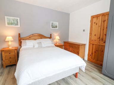 A bedroom with a wooden double bed and two bedside tables with lamps at 17 Clover Hill in Killorglin County Kerry