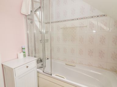A bathroom with a bathtub shower combination and a white cabinet at 17 Clover Hill in Killorglin County Kerry