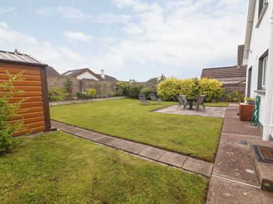 A backyard with green grass a shed lawn chairs and a table with chairs at 17 Clover Hill in Killorglin County Kerry
