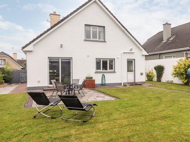 A backyard with lawn chairs a table and chairs and a white house at 17 Clover Hill in Killorglin County Kerry