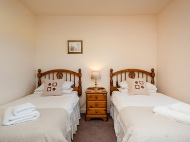 A bedroom with two beds and a nightstand at Bramble Cottage in Akeld near Wooler