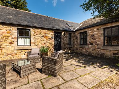 An outdoor seating area with a stone wall at Bramble Cottage in Akeld near Wooler