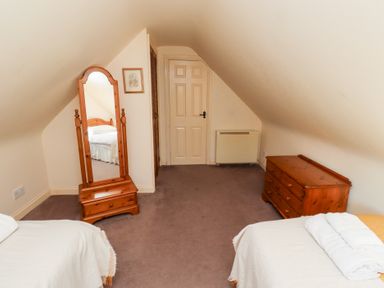 A bedroom with two single beds a wooden dresser and a standing mirror at Tile Rouge in Wooler